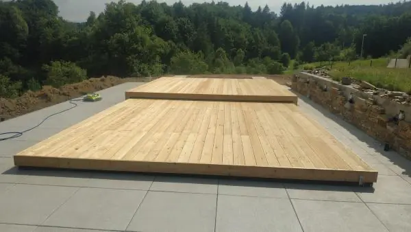 <p>Zde je vidět příkladná ukázka toho, jak designové zastřešení Slide Wood spojuje celý koncept zahrady a rodinného domu. Zastřešení je tvořeno ze dvou dílů, přičemž menší díl zajíždí do většího dílu a oba díly se odsunou za hranu bazénu. Na povrch zastřešení se použily přírodní dřevěná terasová prkna, která se ukazují taktéž na fasádě domu. Přirozenou přírodní atmosféru podtrhává kámen kolem terasy u bazénu.</p>
